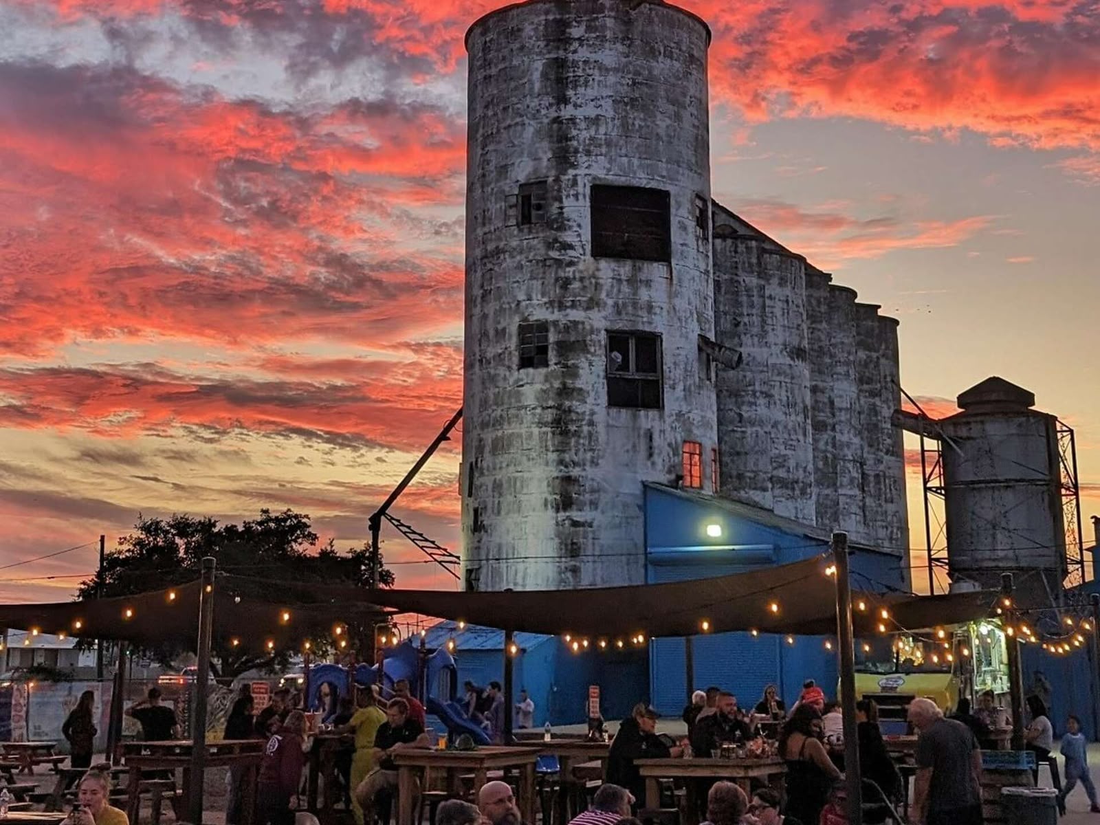 No Label Brewing outdoor beer garden at sunset with historic silos and string lights